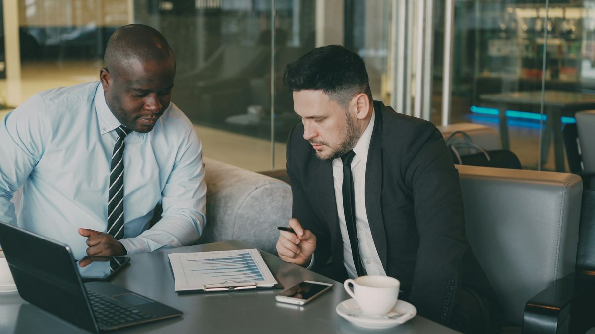 Two professionals in a meeting review documents together at a table.